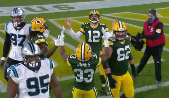 Aaron Rodgers, Davante Adams and Aaron Jones look up, hands raised, as they celebrate a touchdown against the Panthers during a 2020 game